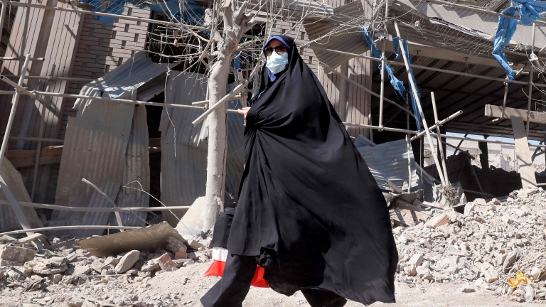 TOPSHOT - A woman walks past a heavily-damaged building near Ferdowsi square in Tehran on March 3, 2026. The United States and Israel started striking Iran on February 28, killing Iran's supreme leader and top military leaders, and prompting autho...