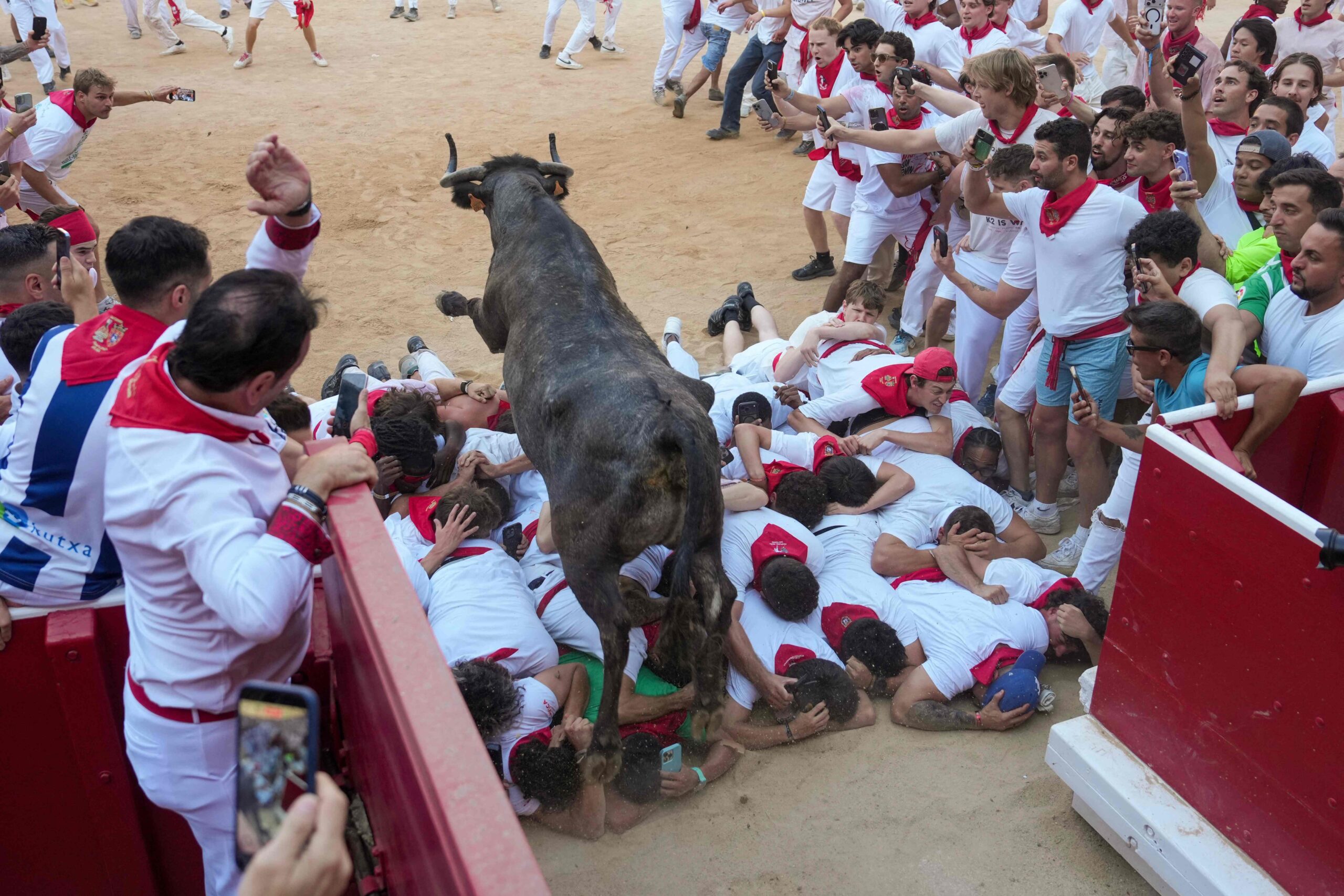 TOPSHOT - A heifer, or young cow, jumps over participants in the bullring as they run and try to dodge the young animal after the first running of the bulls of the San Fermin festival in Pamplona, northern Spain, on July 7, 2026. Thousands of peop...