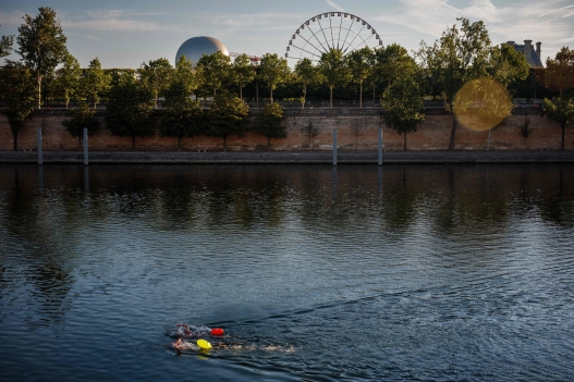 Competitors swim by the Jardin des Tuileries gardens as they take part in a 8km open-water swimming race on the River Seine during the Swimming Across Paris ("Traversée de Paris à la nage") event in Paris on July 12, 2026. (Photo by Dimitar DILKOFF / AFP)