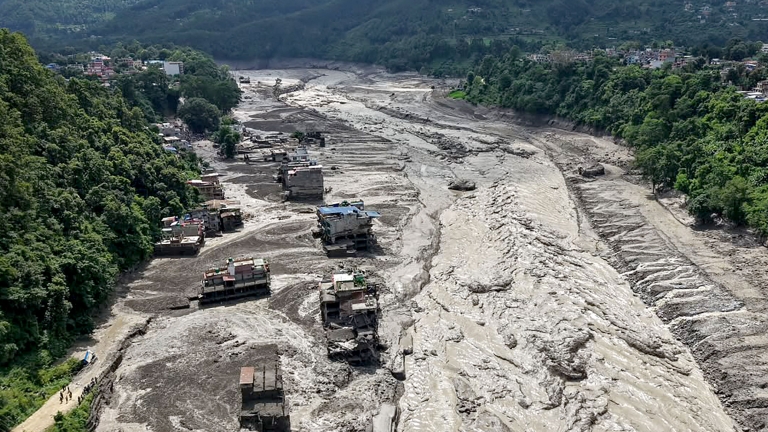 TOPSHOT - Houses lie partially submerged in muddy water along a riverside after flash floods at Trishuli Bazar in Nepal's Nuwakot district on August 26, 2026. A massive flood swept through Nepal's northern Rasuwa district on August 26, damaging ro...